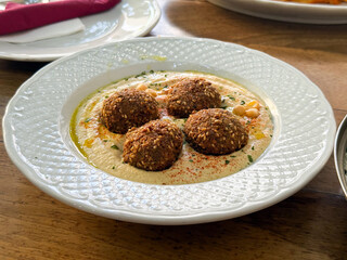 Falafel served on creamy hummus with sesame, olive oil, and spices. Middle Eastern cuisine, flavor, and healthy balance of traditional food culture.