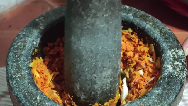 Pound the chili paste with a stone mortar.