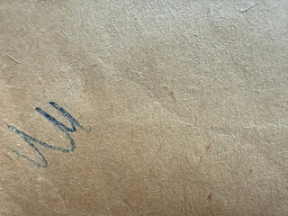 Old brown paper with a doodle and space for text. Textured cardboard background with visible fibers, rough texture reflecting soft light