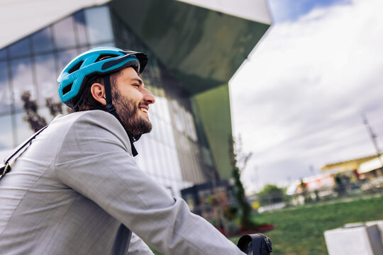 Young businessman riding an electric bike to work, wearing a professional suit.