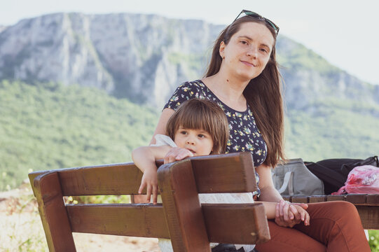 A mother and a daughter are having a picnic in nature