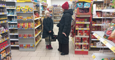 A woman and a girl are talking in a grocery store between aisles