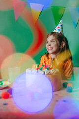 Happy little girl celebrating birthday sitting at decorated table