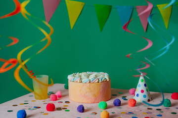 Birthday cake on the decorated table over green wall