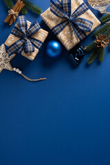 Vibrant vertical Christmas scene featuring neatly wrapped gifts with blue plaid ribbons, pine...