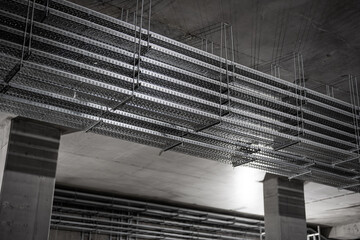 Multi-level metal cable trays suspended under concrete ceiling in industrial building