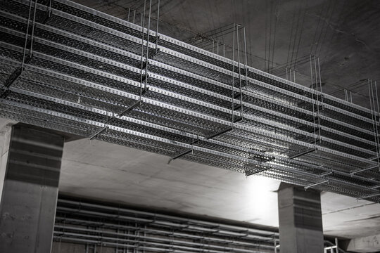 Multi-level metal cable trays suspended under concrete ceiling in industrial building