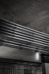 Multi-level metal cable trays suspended under concrete ceiling in industrial building