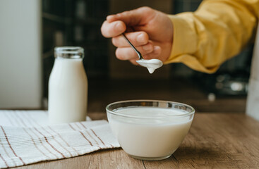 Close-up of male hand in yellow sleeve scooping yogurt from a bowl