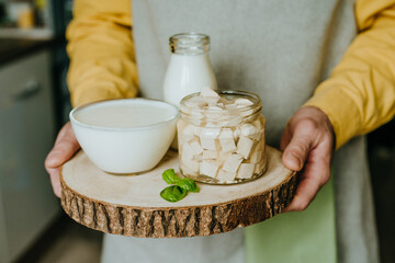 Close up of male hands holding wooden tray with tofu, yogurt and milk