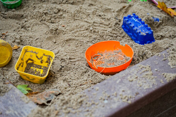 Colorful toys scattered in outdoor sandbox play area view