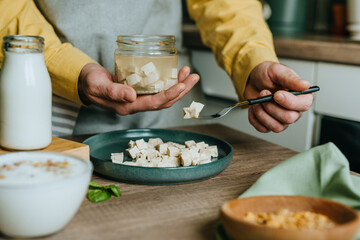 Males hands holding tofu on a fork over a jar