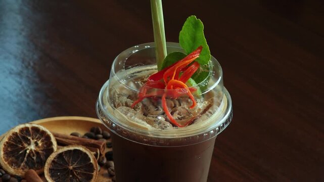 Coffee mixed with lemon, chili, galangal, lemongrass, kaffir lime leaves, Tom Yum flavor in a tall glass with ice.
