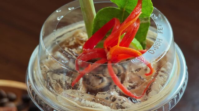 Coffee mixed with lemon, chili, galangal, lemongrass, kaffir lime leaves, Tom Yum flavor in a tall glass with ice.