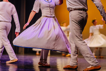 Latvian folk dancers in traditional costumes performing on stage, showcasing vibrant movements and cultural heritage through rhythmic dance
