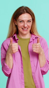 Middle-aged woman confidently points at herself with proud smile, expressing motivation desire to be picked or acknowledged. Young adult girl isolated on blue background shows self-assurance eagerness