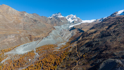 A drone view above Zermatt reveals the stunning Matterhorn region with its famous lakes, golden larches, and a deep blue autumn sky in perfect harmony.