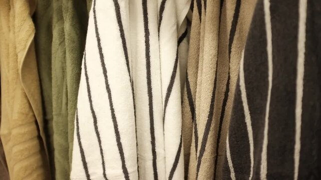 Soft clean folded striped towels hanging on a hook. Colorful striped towels in a  laundry room, in bathroom, on a store shelf.