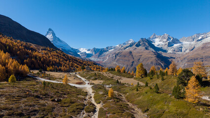 A drone view above Zermatt reveals the stunning Matterhorn region with its famous lakes, golden larches, and a deep blue autumn sky in perfect harmony.