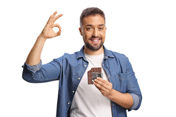Young man holding a chocolate bar and gesturing ok sign
