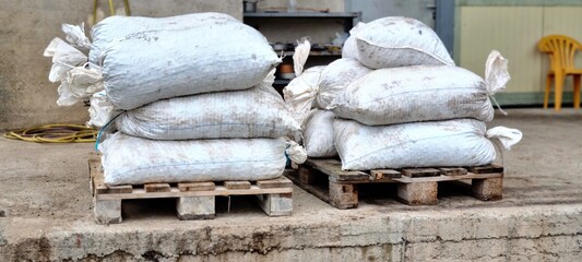 Stacks of sacks filled with freshly harvested olives on wooden pallets outside an olive mill