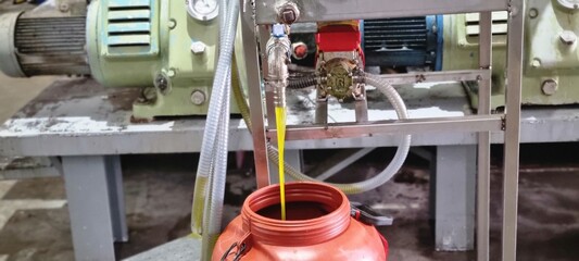 High-resolution photo showing fresh extra virgin olive oil flowing from a stainless steel extractor into a container inside a modern olive oil mill