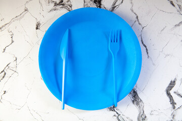 Plate and cutlery on white marble background, top view