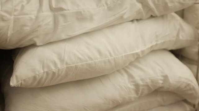 New soft fluffy pillows arranged in stack on a store shelf, home closet or laundry room. Comfortable modern pillows for a household.
