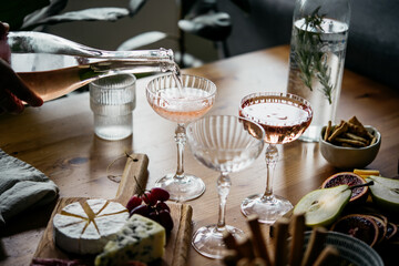 Pouring rose wine with classic snacks of cheese, bread and olives. Party or anniversary celebration.