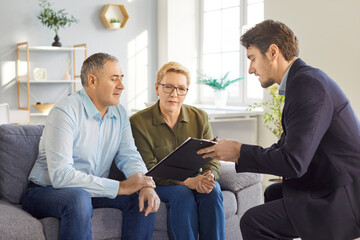 Senior couple sitting with financial advisor, discussing real estate or investment plans. Young professional explaining contract details and helping pensioners make informed decisions for retirement.