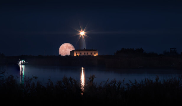 Full moon rising behind the lighthouse of Goro, Po Delta, Italy