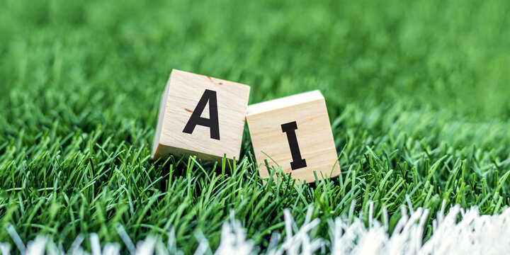 Word AI or Artificial Intelligence concept, written with wood cubes. Cubes lying on artificial grass, the concept of technology and progress