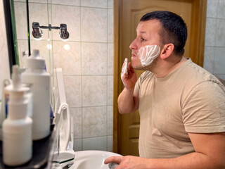 Man shaving in bathroom mirror