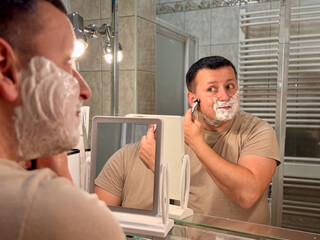 Man shaving in bathroom mirror