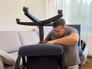 Man assembling an office chair in a bright living room