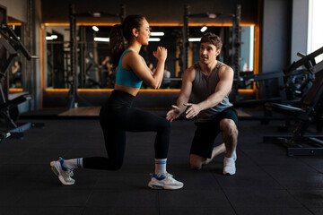 Woman doing squats and lunges exercises while trainer providing guidance, lady focused on improving...