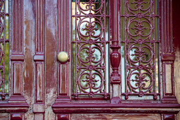 Ornate wooden door with intricate wrought iron details and a polished brass knob, showcasing craftsmanship and elegance in architectural design, inviting curiosity and admiration