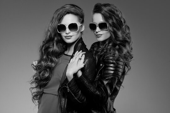 Sisters twins in hipster sun glasses laughing Two fashion models Women smiling positive Friends group having fun, talking Youthful friendship youth adults people culture concept Young girls rock party