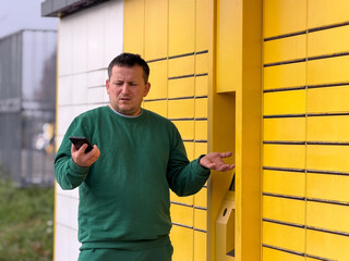 Man confused by delivery locker while using smartphone