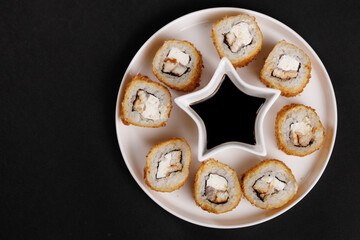 Crispy sushi rolls with cream cheese and soy sauce on star plate
