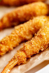 Closeup of golden crispy breaded shrimp on parchment paper