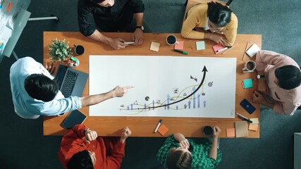 A top-down view of a diverse group of professionals engaged in a business meeting, discussing data trends and strategic growth solutions around a wooden table. Raster - Powered by Adobe