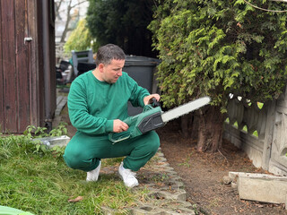 Man inspecting chainsaw in garden