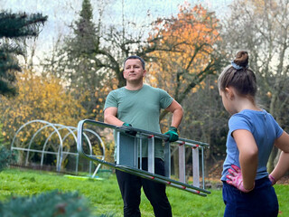 Man and girl in garden with ladder