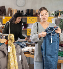 Woman picks up clothes and chooses trousers. Changing wardrobe, shaping style of clothing, filling wardrobe with modern stylish clothes. Chain store of affordable clothing. Style and fashion type look