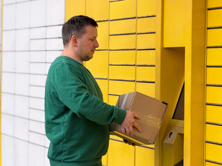 Man using yellow parcel locker for package delivery