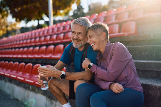 Happy mature couple having fun while relaxing on staircase after outdoor sports training. - Powered by Adobe