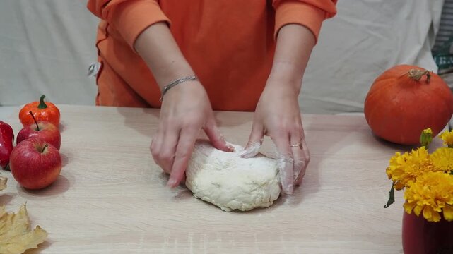 A girl is making apple pie at home. Autumn fall baking background with pumpkins, apples, nuts, food ingredients and seasonal spices. Cooking pumpkin or apple pie for Thanksgiving and autumn holidays, 