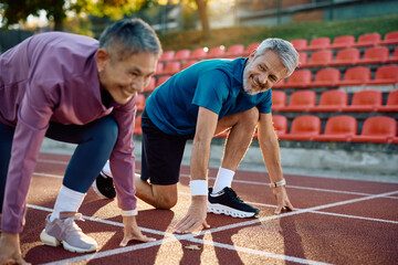 Mature couple of runners on start line getting ready to race each other.