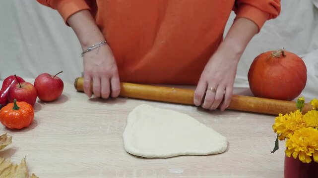 A girl is making apple pie at home. Autumn fall baking background with pumpkins, apples, nuts, food ingredients and seasonal spices. Cooking pumpkin or apple pie for Thanksgiving and autumn holidays, 